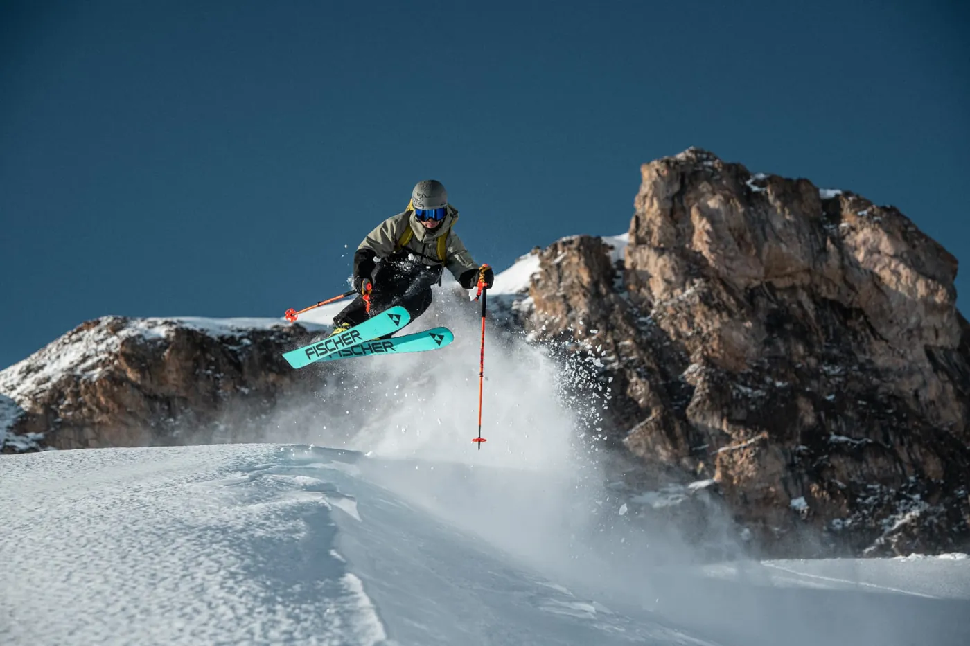 Skifahrer springt im Tiefschnee vor Felsen in Ischgl